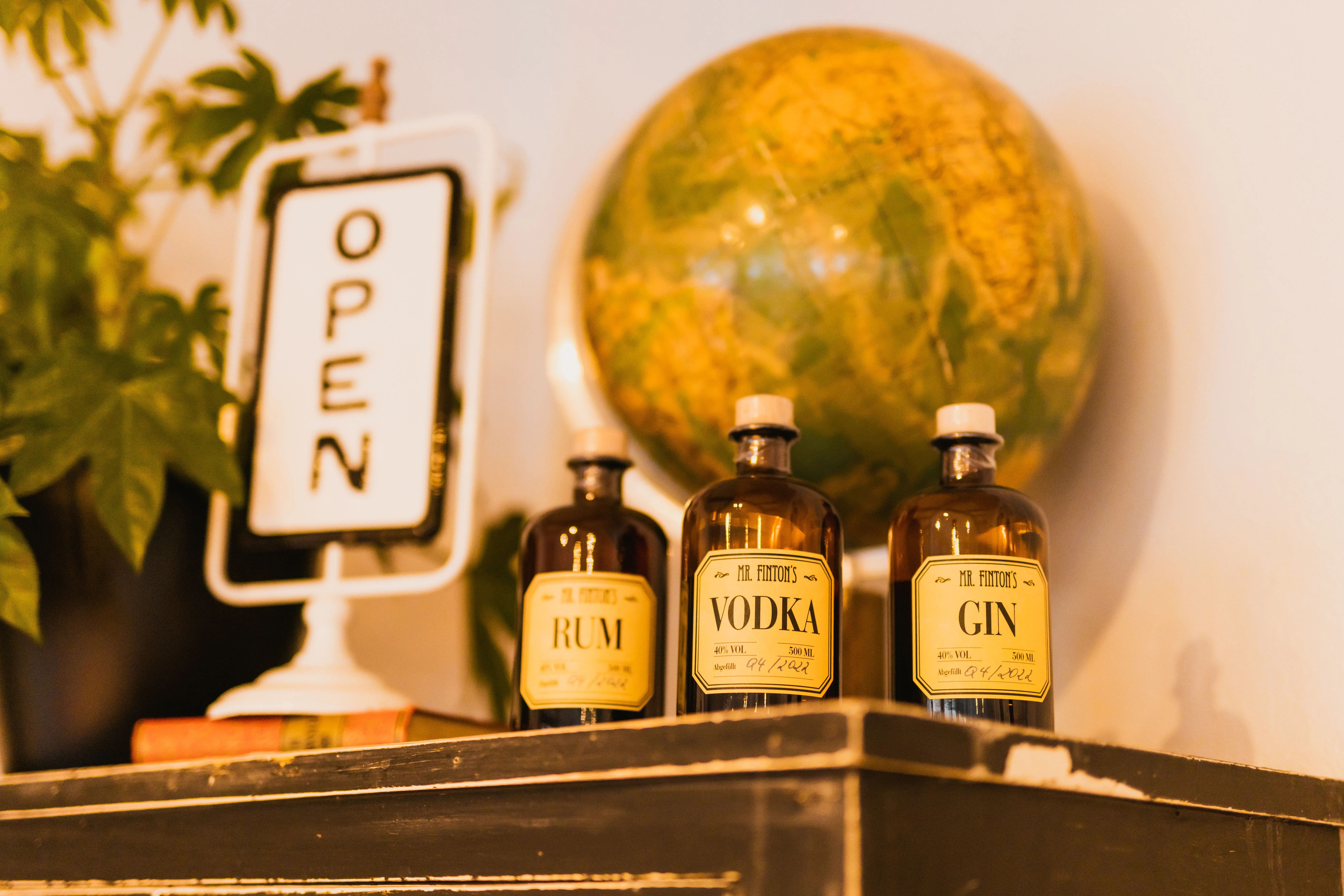 Vintage-Flaschen mit Rum, Vodka und Gin vor altem Globus an der Bar