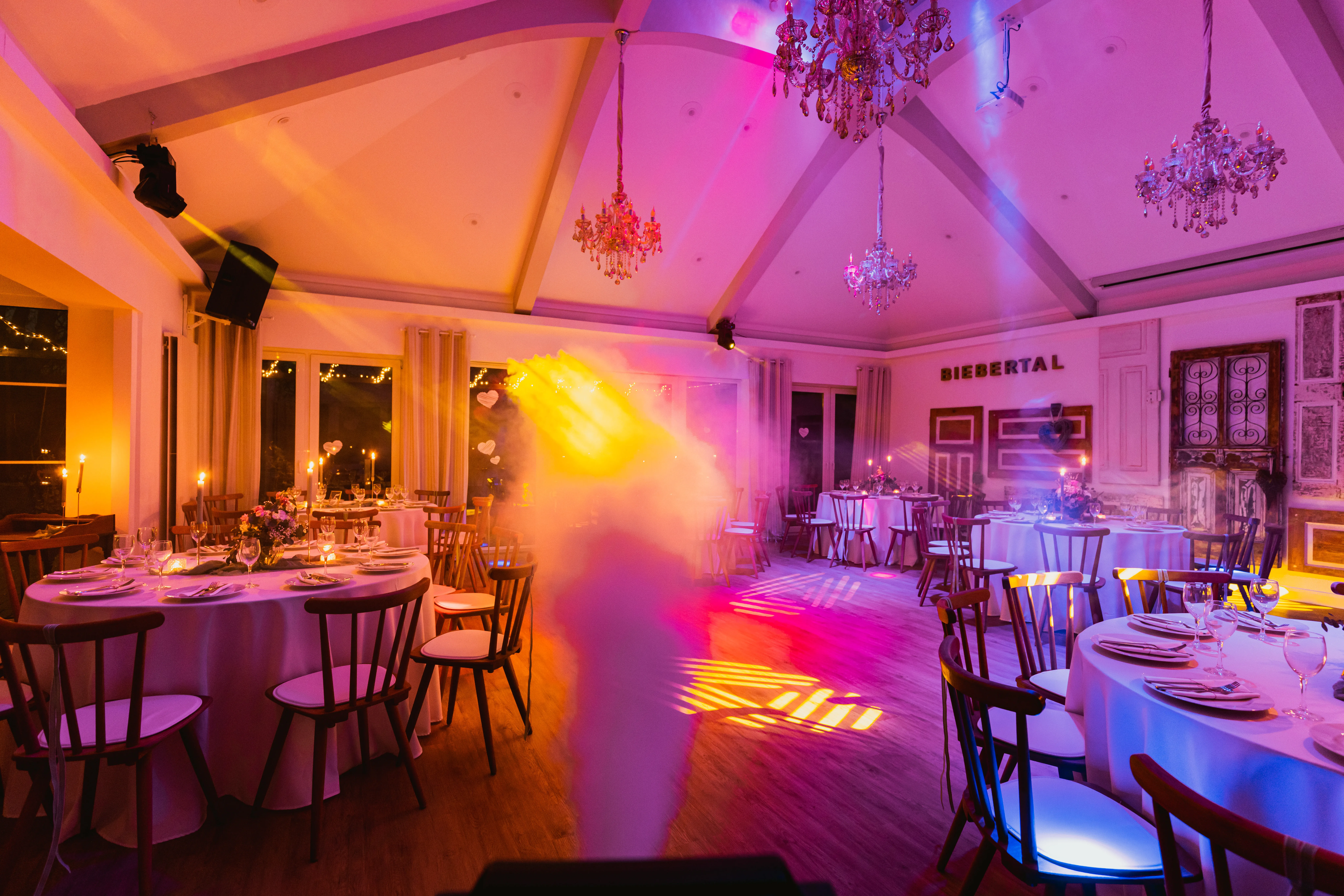 Festlich gedeckter Festsaal im Hotel Biebertal mit Kronleuchtern, Kerzen und warmer rosa-goldener Lichtstimmung