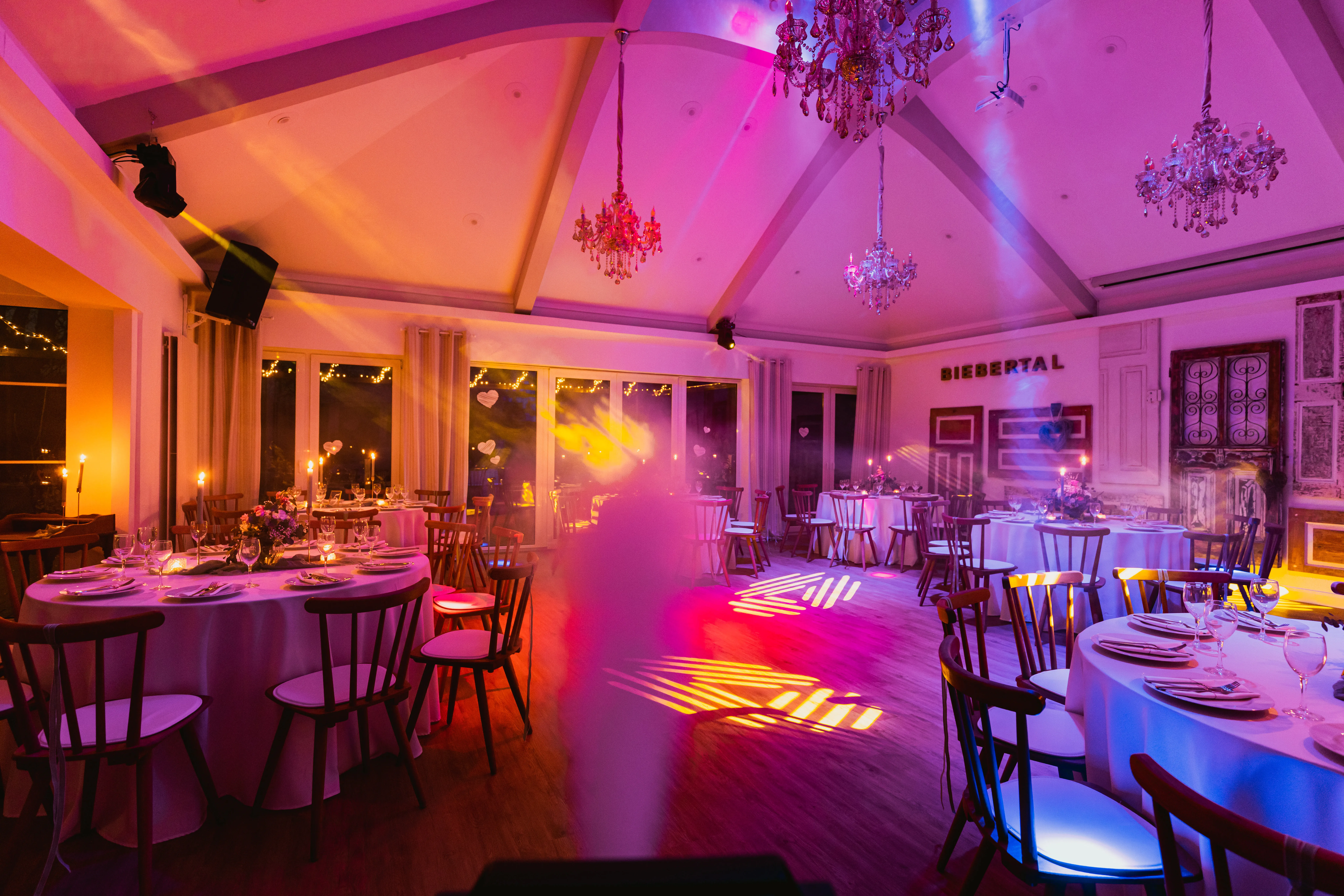 Festsaal bei Nacht mit Nebeleffekt, orange-pinken Lichtstrahlen und Projektionen auf der Tanzfläche