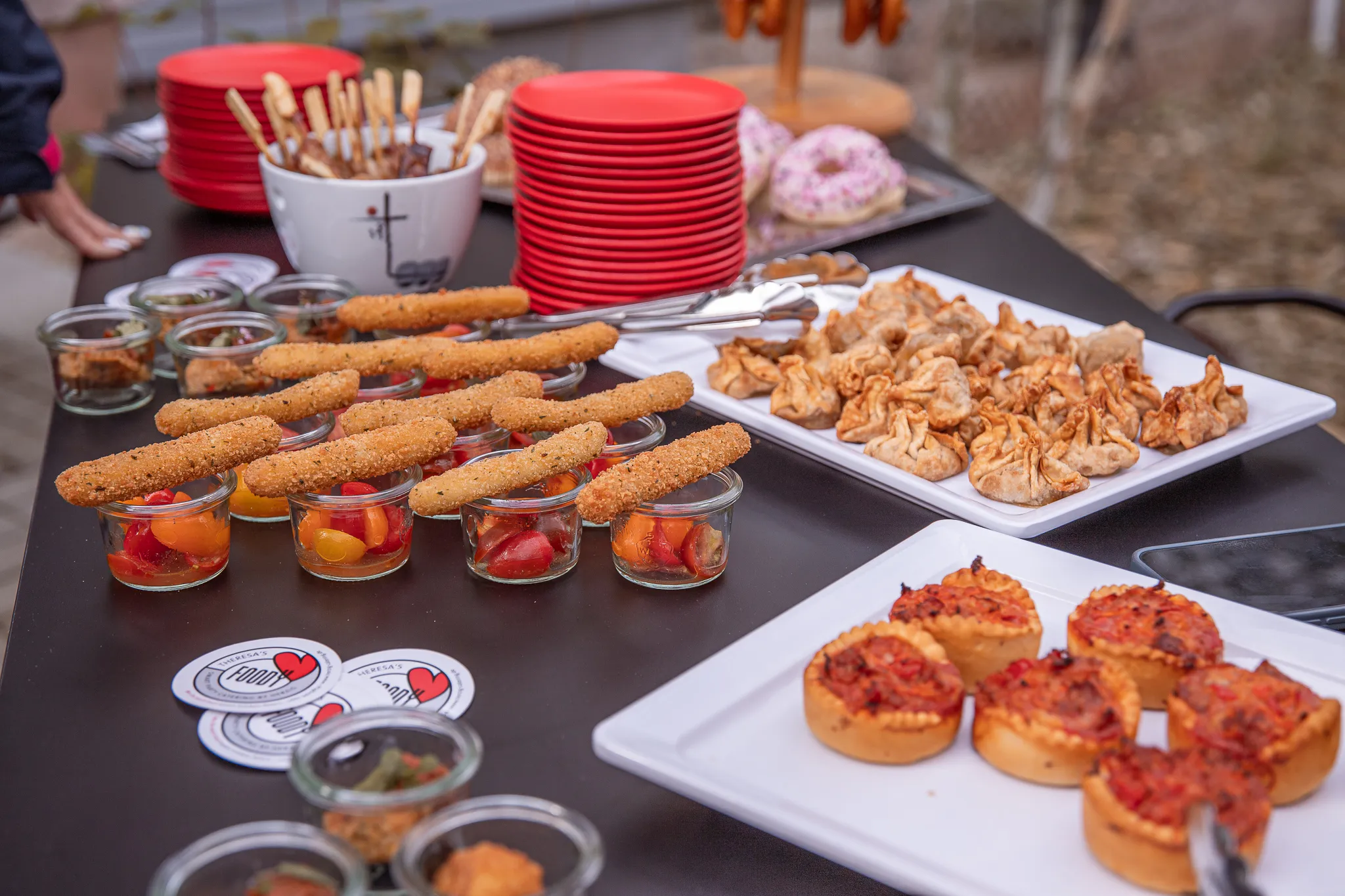 Fingerfood-Buffet im Freien mit Mozzarella-Sticks im Glas, Teigtaschen und Mini-Tartelettes