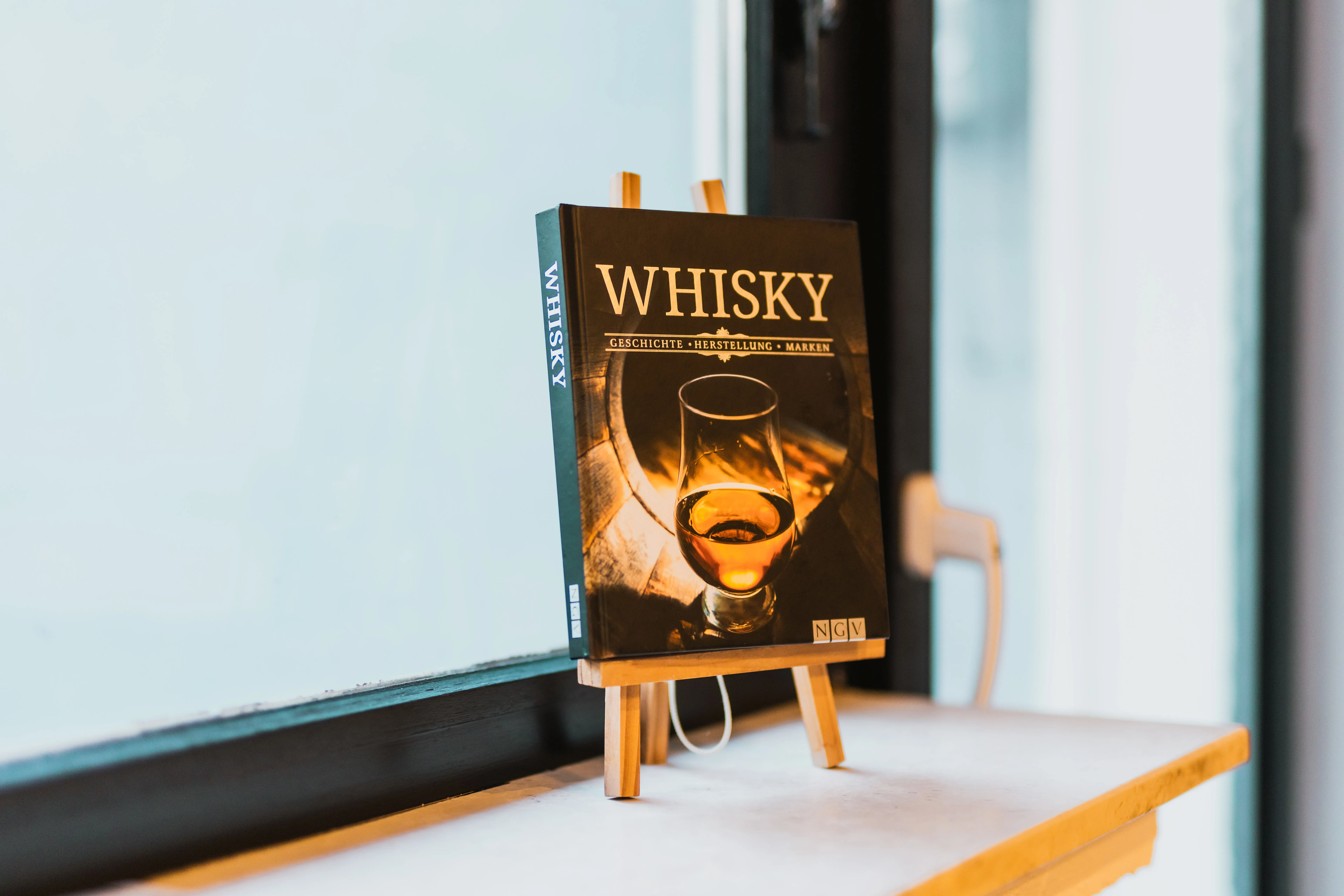 Whisky-Buch auf kleiner Staffelei an der Fensterbank der Bar